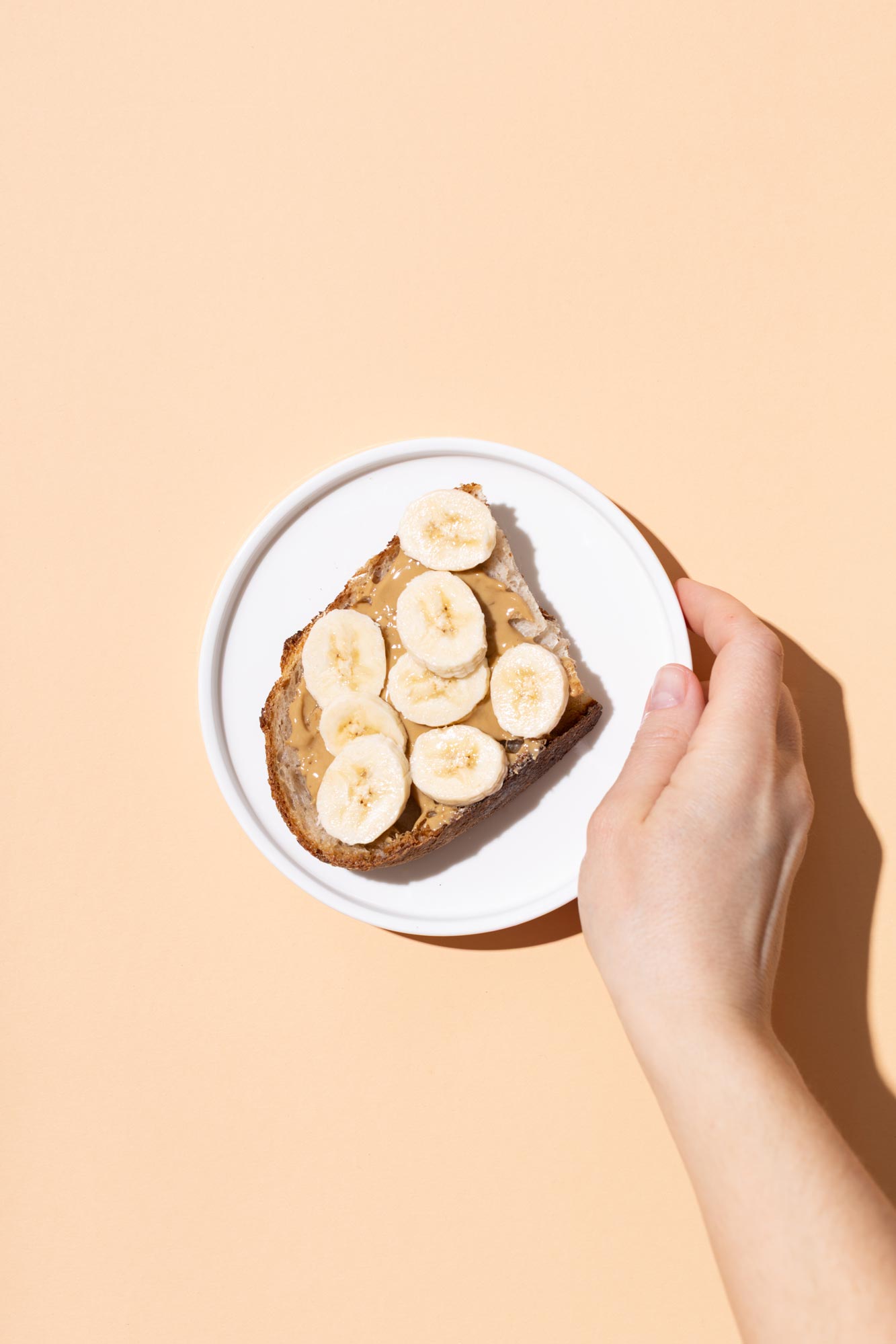 Female hand holding plate with peanut butter banana toast