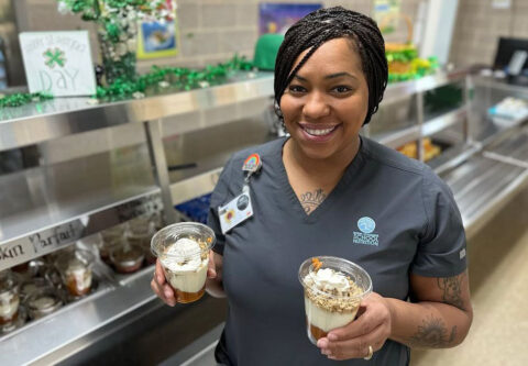 woman holding two cups of dessert made with peanuts