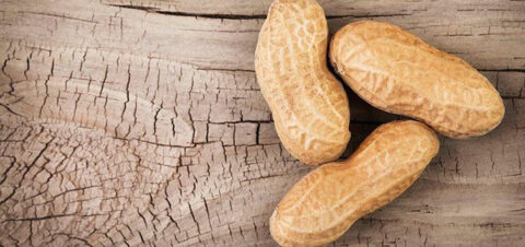 three unshelled peanuts on a wooden surface.