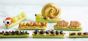 sticks of celery with peanut butter and fruits on top.