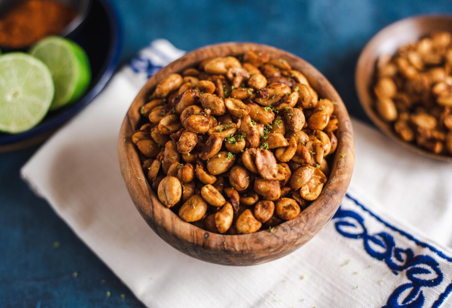 Bowl of chili lime peanuts on white and blue embroidered napkin