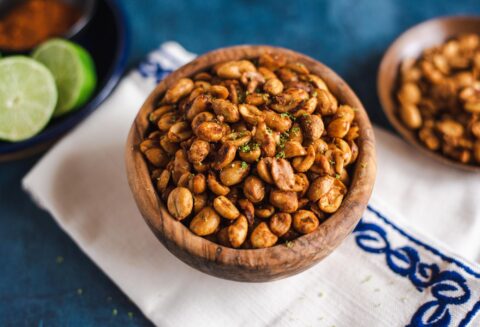 Bowl of chili lime peanuts on white and blue embroidered napkin