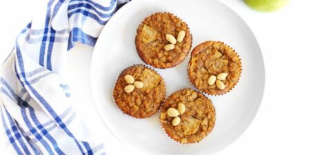 a white plate topped with four apple muffins.