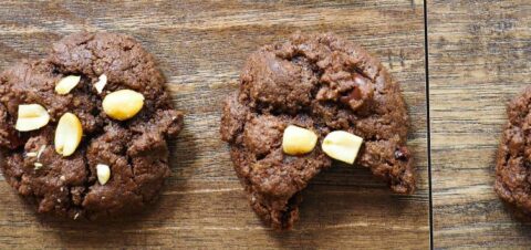 two chocolate cookies crusted with peanuts.
