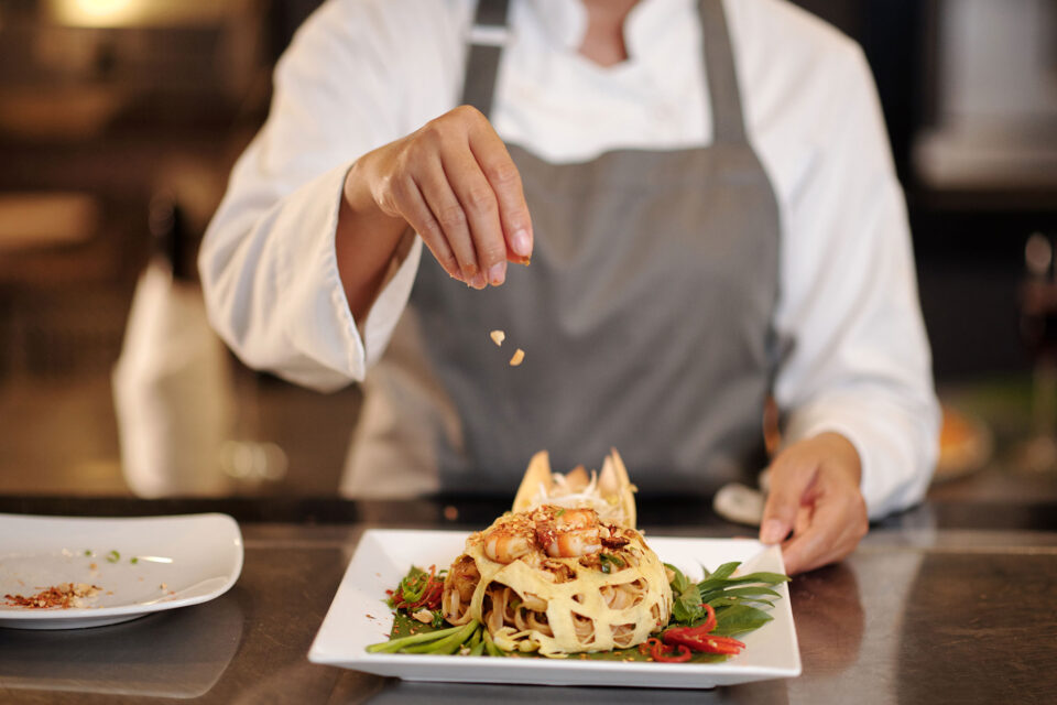 Cook Garnishing Pasta with Crushed Peanuts